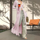 Person wearing a long pink knitted cardigan outdoors